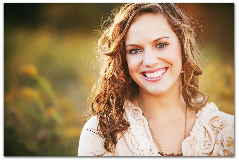 beautiful senior girl in field vintage jewelry and natural sweater makes for perfect tones and beautiful sunlight