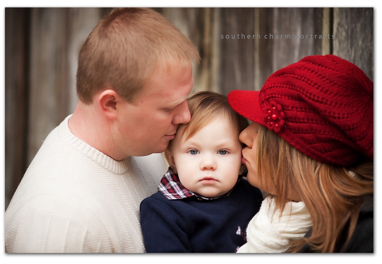 mother and father kissing son on sides of head