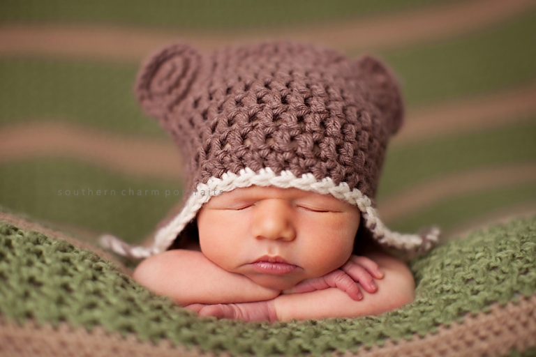 baby sleeping with head on arms with teddy bear hat